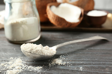 Fototapeta na wymiar Coconut flour in metal spoon against blurred background