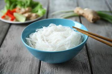 Plate of tasty rice noodles with vegetables on wooden table