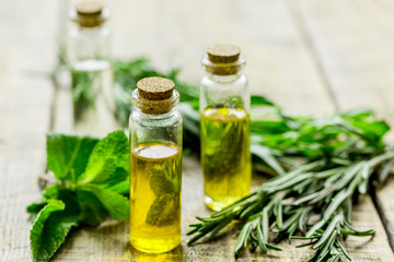 organic oil in bottle with rosemary and mint on light table background