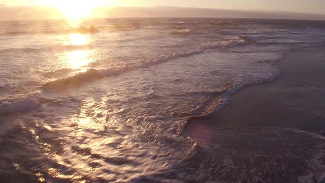 Aerial view of beach waves at sunset