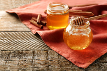 Cinnamon and honey in jars on table
