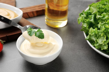 Delicious mayonnaise in bowl and spoon on kitchen table