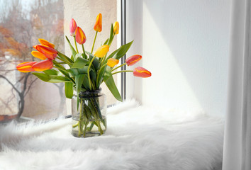 Vase with beautiful tulips on windowsill