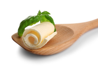 Delicious butter curl and basil leaves in wooden spoon on white background, closeup