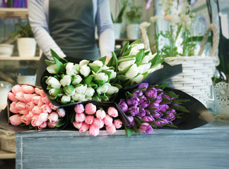 Female florist standing near counter with beautiful bouquets in flower shop