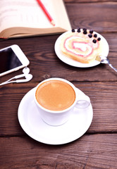 cup of coffee and a mobile phone on a brown table