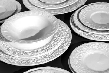 Set of white ceramic dinner relief plates on black background