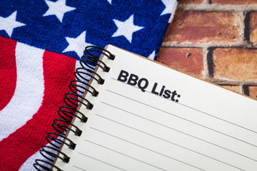 BBQ concept on notebook with brick background and red, white and blue banner for a patriotic themed event