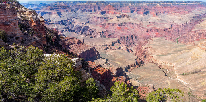 Panoramic view of Grand Canyon at Mather Point, with small people silhouettes on the top of the cliff, showing the vastness of Grand Canyon National Park in Arizona, USA.
