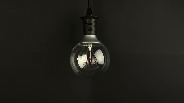 turn on and turn off, with blinking effect, retro vintage light bulb with led technology built-in on warm light yellow tint and black background, energy saving with old style atmosphere concept