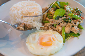 Rice topped with stir-fried pork and basil with  Sunny Side Up 
