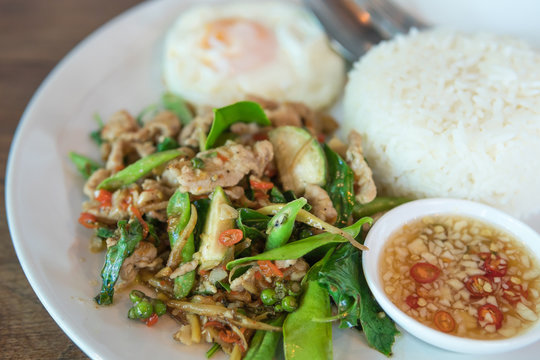 Rice topped with stir-fried pork and basil with  Sunny Side Up 
