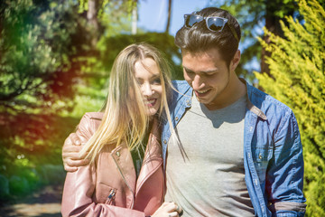Boyfriend and girlfriend standing in countryside in green luscious field, strolling and cuddling, showing romantic love