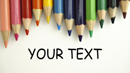 Colored pencils on white paper with word YOUR TAXT. back to school concept