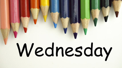 Colored pencils on white paper with word WEDNESDAY. back to school concept