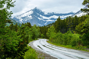 Stormy Mountain Road - A stormy spring day view of a winding road in Glacier National Park,...