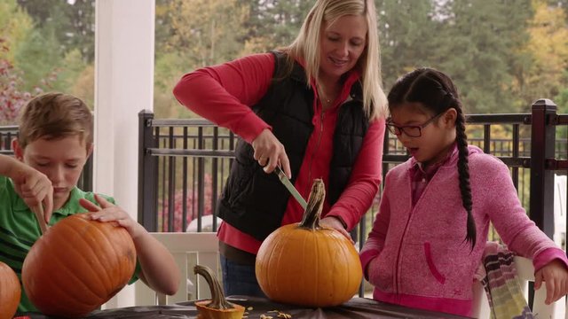 Mom and kids carving pumpkins for Halloween