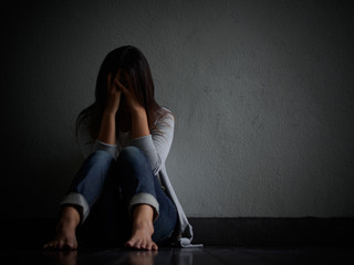 sad woman hug her knee and cry. Sad woman sitting alone in a empty room.