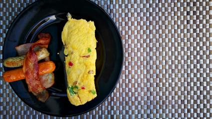 Served healthy protein breakfast with sausage and omelet on black plate. Flat-lay view and have some space for write wording