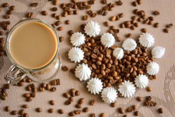 a glass of latte and a heart of meringue and coffee bean