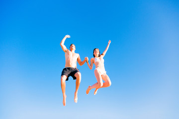 Young Couple In Swimwear Jumping