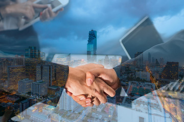 Double Exposure of a businessman handshake on Aerial view of Bangkok modern office buildings, condominium in Bangkok city downtown with twilight sky , Bangkok , Thailand