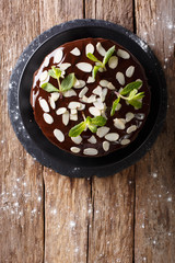 Homemade chocolate cake with almonds and mint closeup on the table. Vertical top view