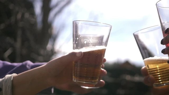 Young people check glass glasses with drinks against the blue sky. HD, 1920x1080. Slow motion
