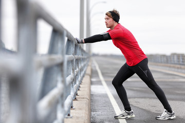 Man runner stretching legs before exercise run outdoors in city urban street during winter. Athlete...