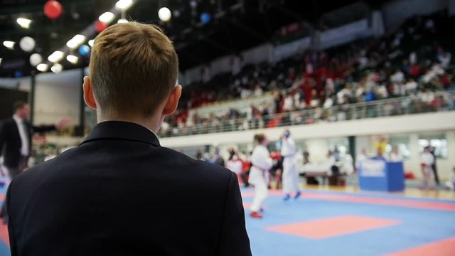 Martial art competitions - man coach-judge looking at karate teenager's fighting