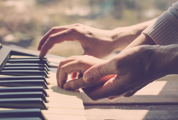 Mother teaches the daughter to play the piano. Concept Mother's Day. Female and children's hands. Vintage toning.