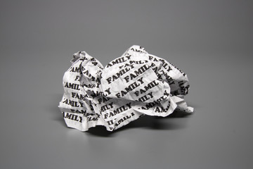 A crumpled paper with the words "family" written all over it on a gray background.