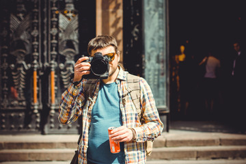 A man with a camera walks around the city photographing the neighborhood. The tourist came to see European sights and take a walk with a good mood