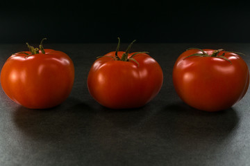 Background food ingredients on black table. Fresh tomatoes,