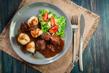 Pork meat stew served with potatoes and vegetable salad