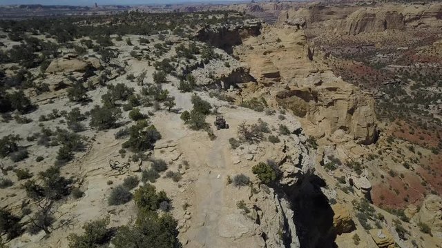 Aerial off road recreation ATV drive dangerous Utah desert trail. Geologic desert landscape. Erosion rock towers, cliffs, and deep canyons. 4x4 all terrain off road vehicle. Dangerous wilderness.