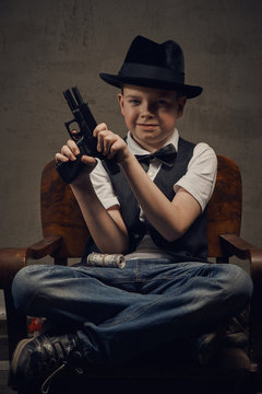 Little boy gangster in hat with weapon