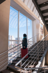 Woman with a suitcase on the stairs of station