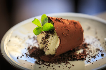Chocolate dessert with mint and cream in the form of a fallen planter.