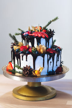 White wedding cake with chocolate and fruits on a stand, Vertical side view
