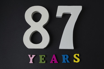 Letters and numbers eighty-seven years old on a black background.