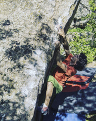 Rock climber reaching for his next hand hold Joshua Tree National Park.