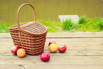 Picnic on the nature in the forest near the river. Wooden table and fruit basket