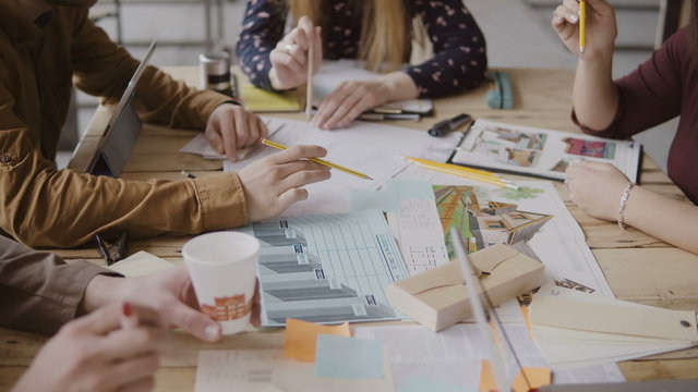 Young creative team working on architectural project. Group of mixed race people sitting at table and discussing.