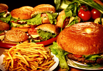 Fast food for large group friends. Unhealthy hamburger and french fries on plate for very hungry group people.