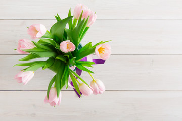 Pink tulips bouquet on white wood background, top view