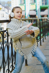 Fototapeta na wymiar Fashion little girl with headphone listening to music outdoor