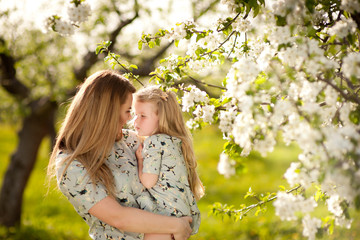 .Mother and daughter are walking in the spring blooming garden, hug, laugh, play