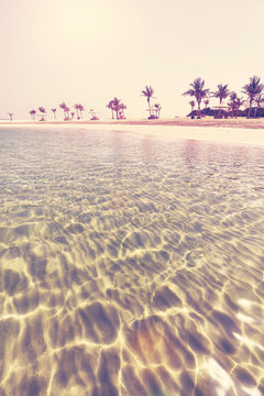 Retro stylized photo of a beautiful beach with crystal clear water, summer holidays concept.