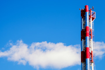 Red and metallic heating plant pipes on background blue sky and the cloud behind